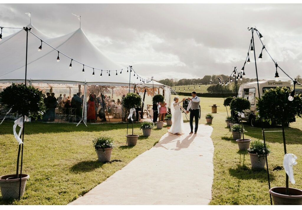 Sailcloth Marquee Wedding with matting walkway and festoon lightin on giant shepherds crooks